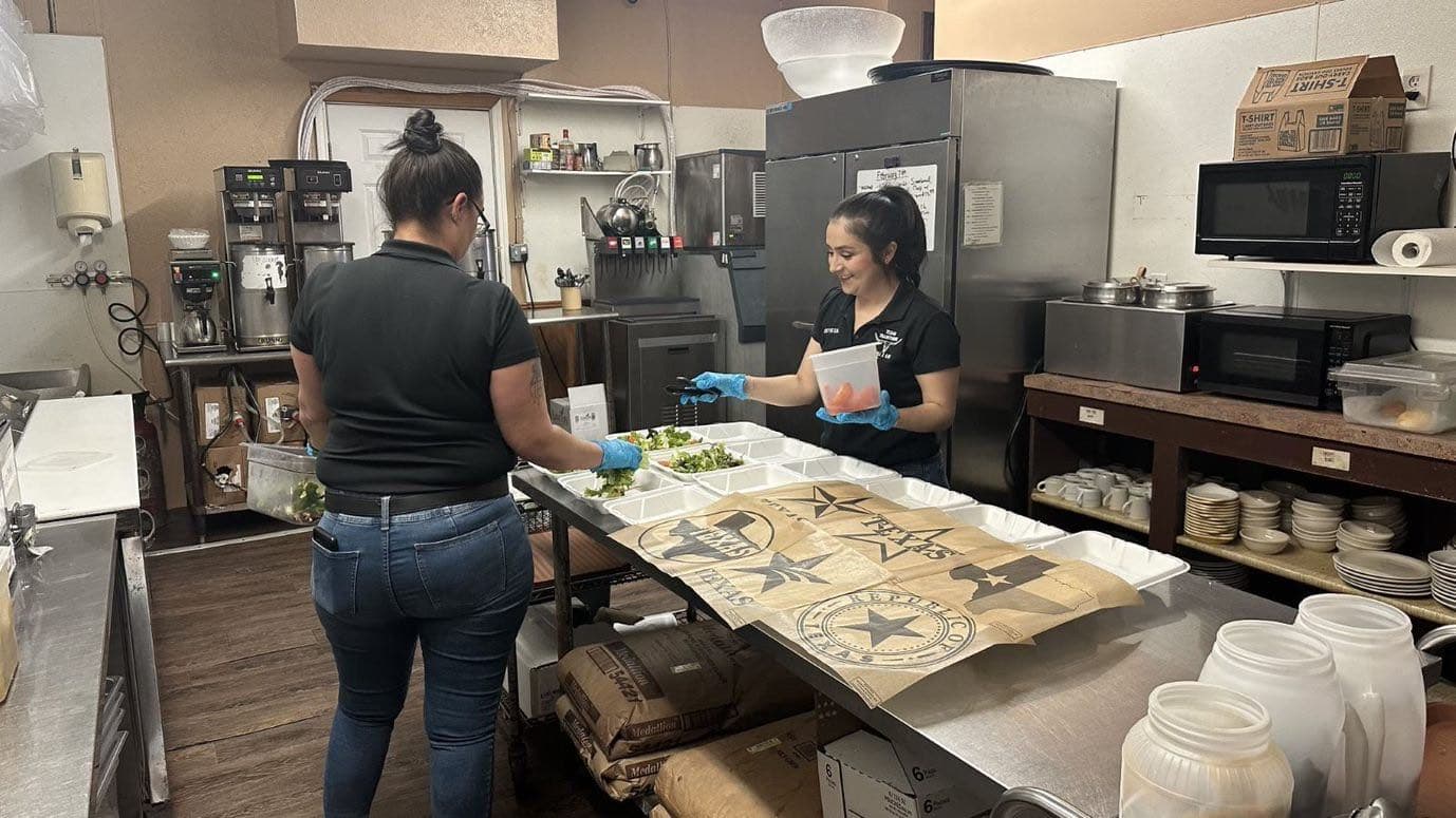 Texas Traditions staff plating catering orders in branded takeout bags